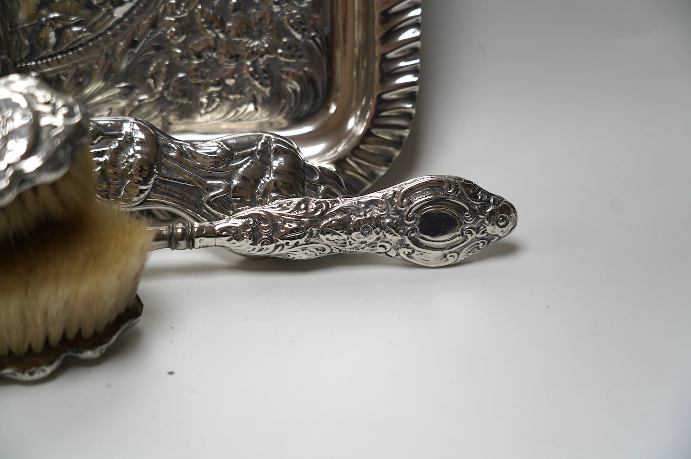 An Edwardian Art Nouveau four piece dressing table set including a tray, Birmingham, 1904, 30.3cm and a similar silver mounted shoe horn. Condition - poor to fair